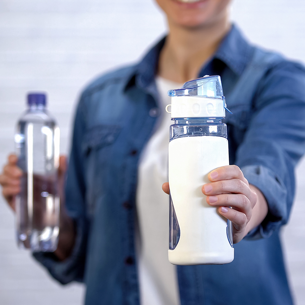 Female choosing reusable thermos instead disposable bottle, plastic pollution